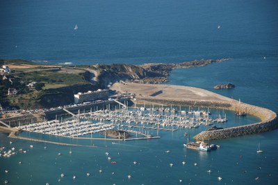 France-NW-St_Cast-Marina a rocky headland sheltering a curved breakwater inside of which is a large marina with many masted boats inside