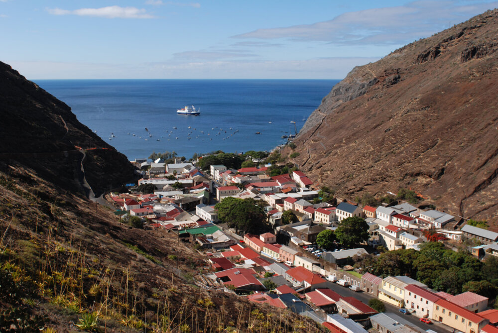 steep valley sides with a bay behind and on the valley floor a town in a narrow strip of land with red roofs