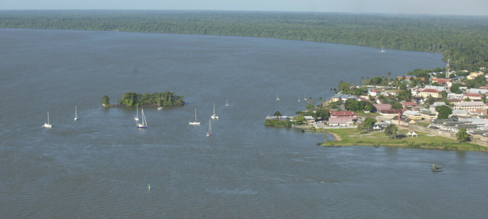 aerial view of an anchorage with a small wooded island on the left and a small settlement on shore to the right